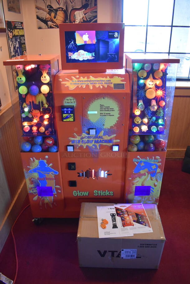 VTail Metal Commercial Floor Style Web Glow Toy Vending Machine on Commercial Casters. Comes w/ Box of Extra Toys. Unit Was In Working Condition When Restaurant Closed. BUYER MUST REMOVE. (Dining Room)