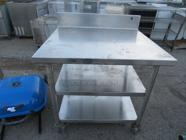 One Stainless Steel Tabel With 2 Stainless Steel Under Shelves, And Back Splash On Casters. 36X32X40