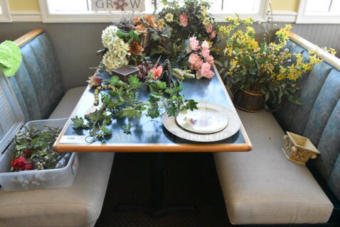 Wall Mount Table w/ Contents Including Spring/Summer Floral Decor. BUYER MUST REMOVE: Bring Tools and Manpower Needed To Remove This Item. (booth room) 